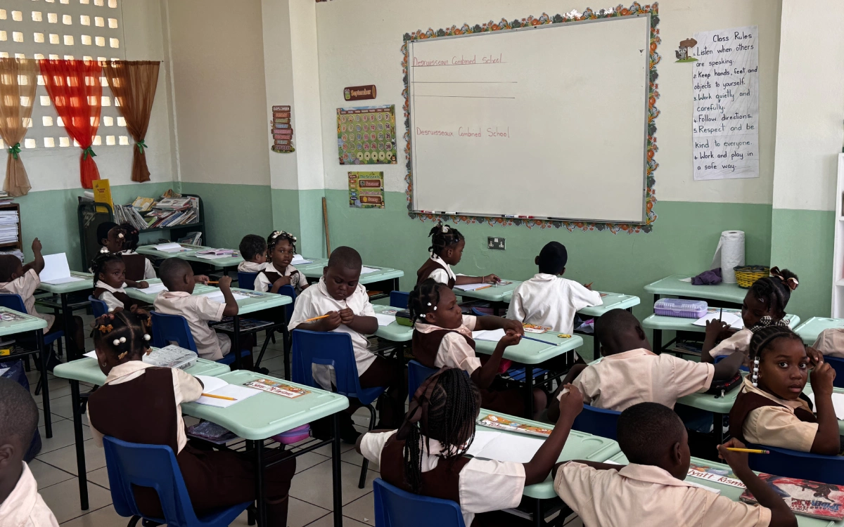 A classroom with students sitting at desks in front of a whiteboard.