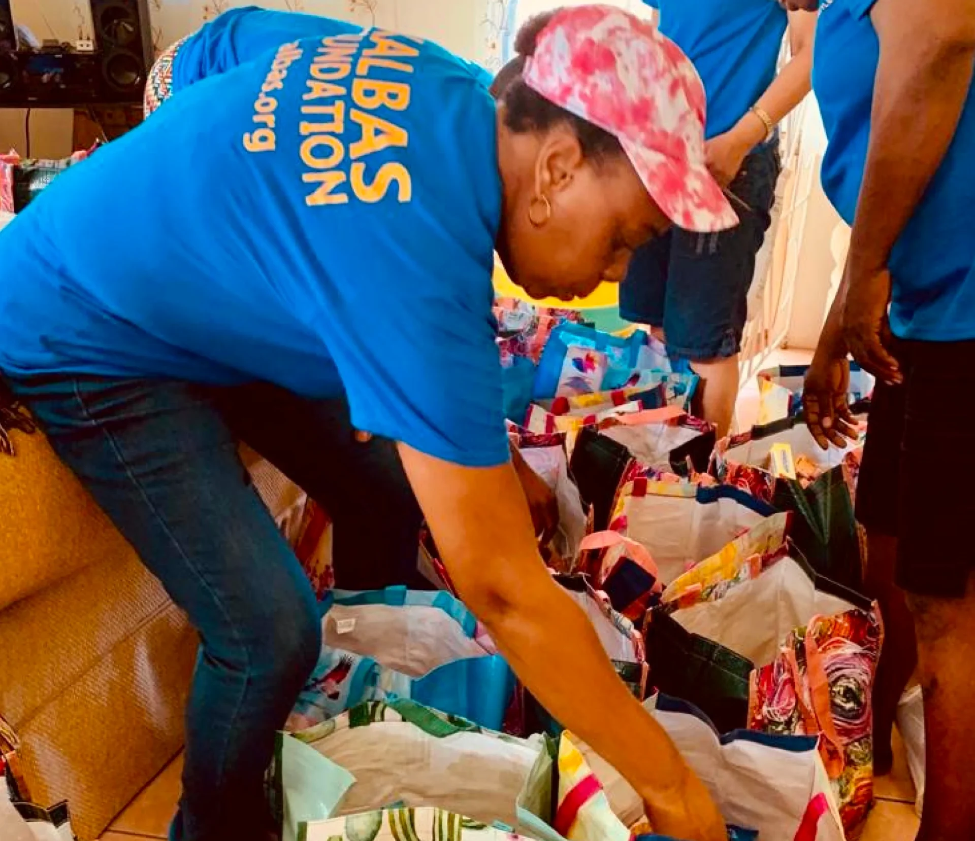 A woman in blue shirt and hat putting together boxes.