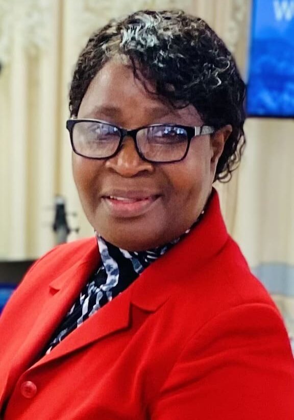 A woman in red jacket and glasses smiling for the camera.