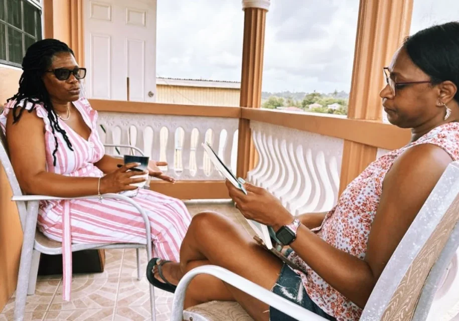 Two women sitting on a porch with their phones.